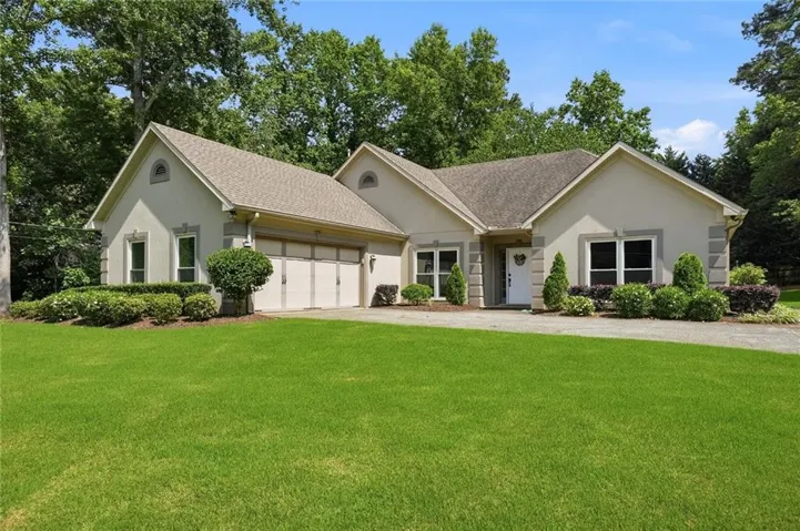 Stucco exterior residence featuring a prominent two-car garage, white framed windows, and a paved driveway
