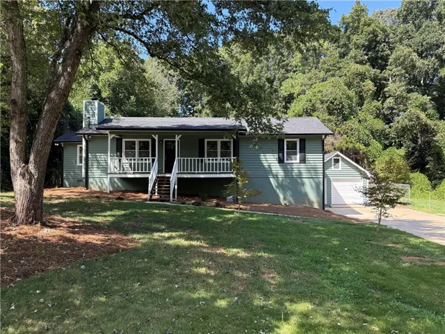 Single-story residence featuring a covered front porch, white railings, and an attached garage