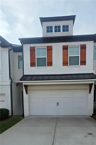Modern townhome exterior featuring white brick and dark metal roofing