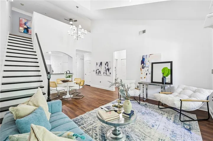 Wood-finish flooring throughout, vaulted ceilings, staircase with black treads and white risers, and an arched doorway