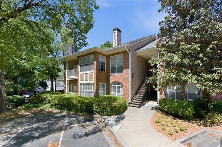 Brick exterior with multiple windows, second-story balcony, and mature landscaping