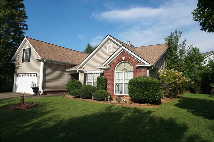 Traditional-style residence featuring a brick facade with an arched window, horizontal siding, and a two-car garage