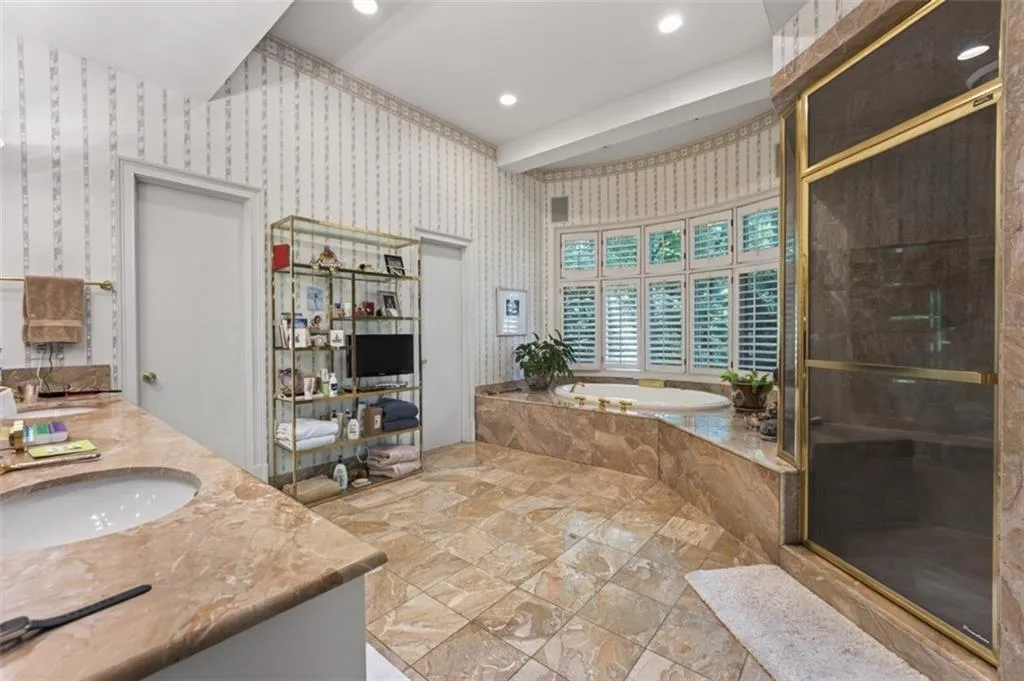 Recessed lighting illuminates the tiled flooring and built-in soaking tub