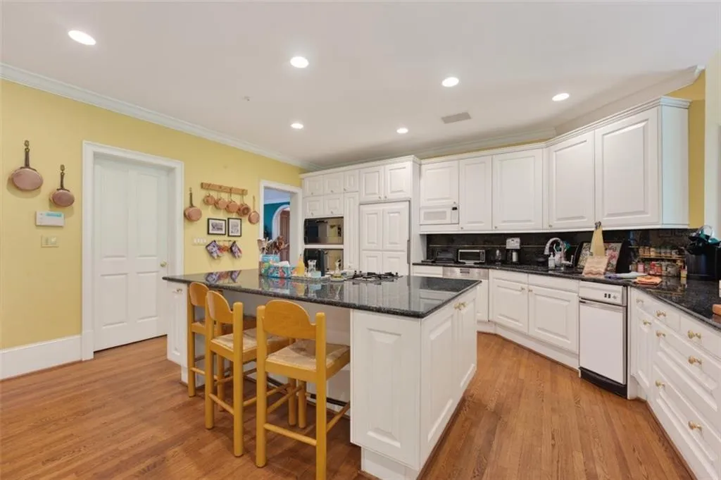 Kitchen featuring wood-finish flooring, white cabinetry, dark countertops, a large island, and recessed lighting