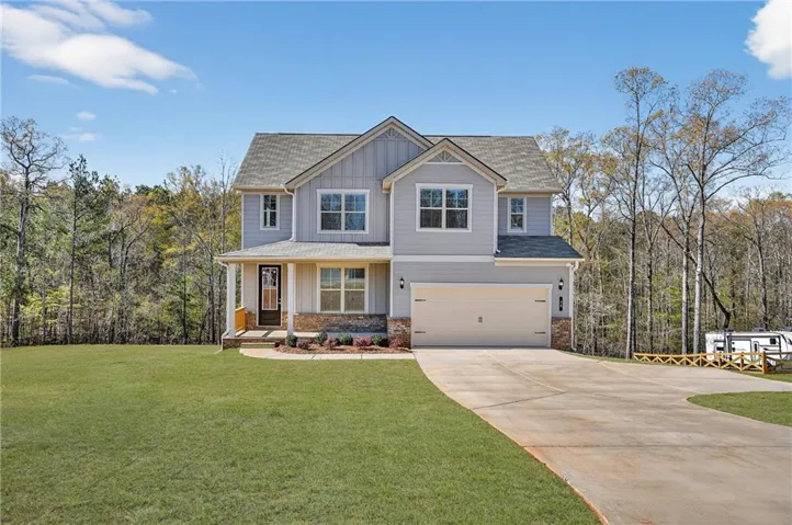 Two-story residence featuring light gray siding with board and batten accents and stone veneer details