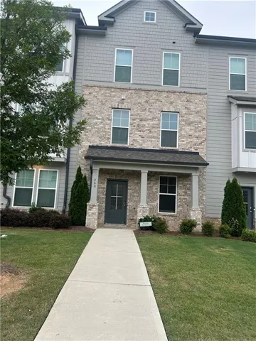 Multi-level townhome featuring a brick facade, gray siding, and an inviting covered porch with columns