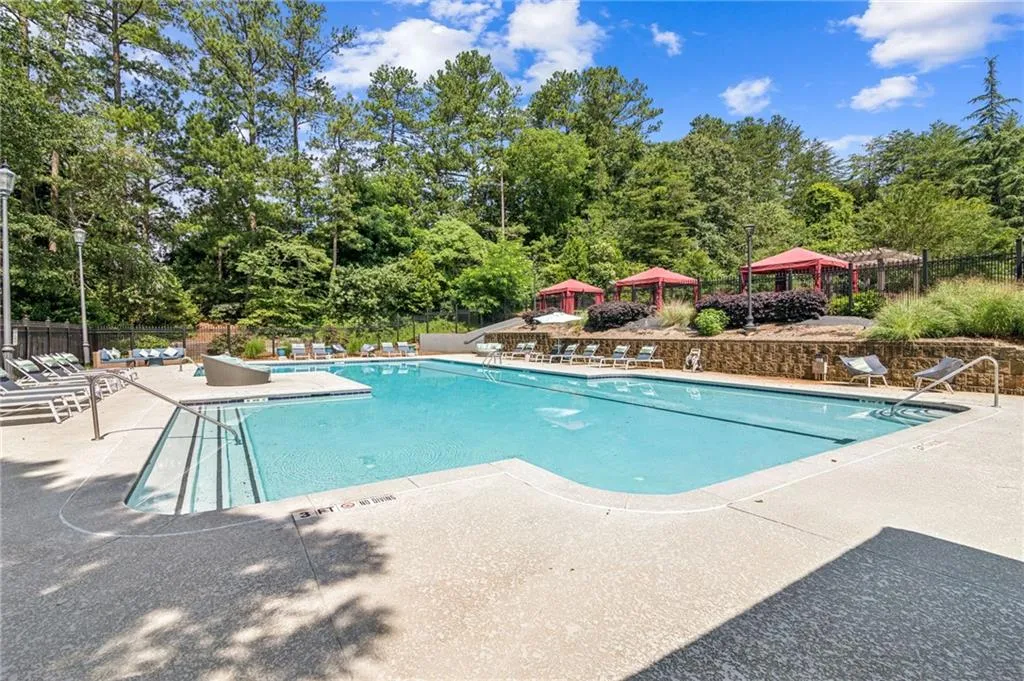 Community pool with a gazebo, a patio area, and view of wooded area Community pool with a gazebo, a patio area, and view of wooded area