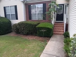Brick veneer exterior with siding accents, mature perimeter landscaping, and a concrete walk to the entry