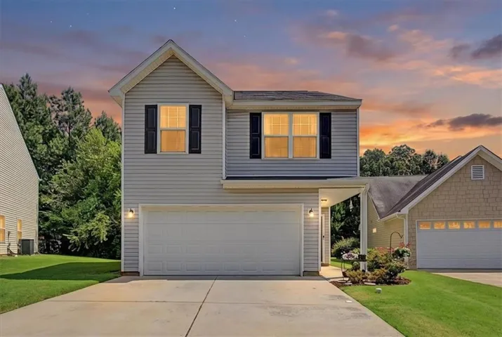 Two-story exterior with light gray siding, attached garage, and black louvered shutters
