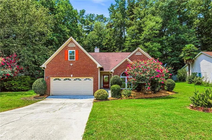 Traditional brick exterior featuring a multi-gabled roofline, an arched window, and a prominent garage with decorative paneling