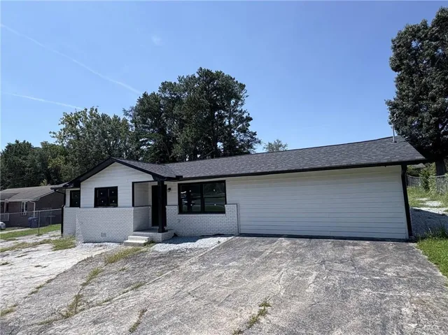 View of front of property featuring brick siding, roof with shingles, and driveway