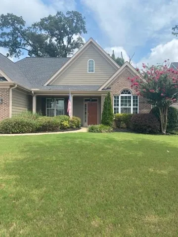 Traditional-style residence featuring a prominent front gable with an arched window, a covered entry porch, and brick and siding exterior finishes