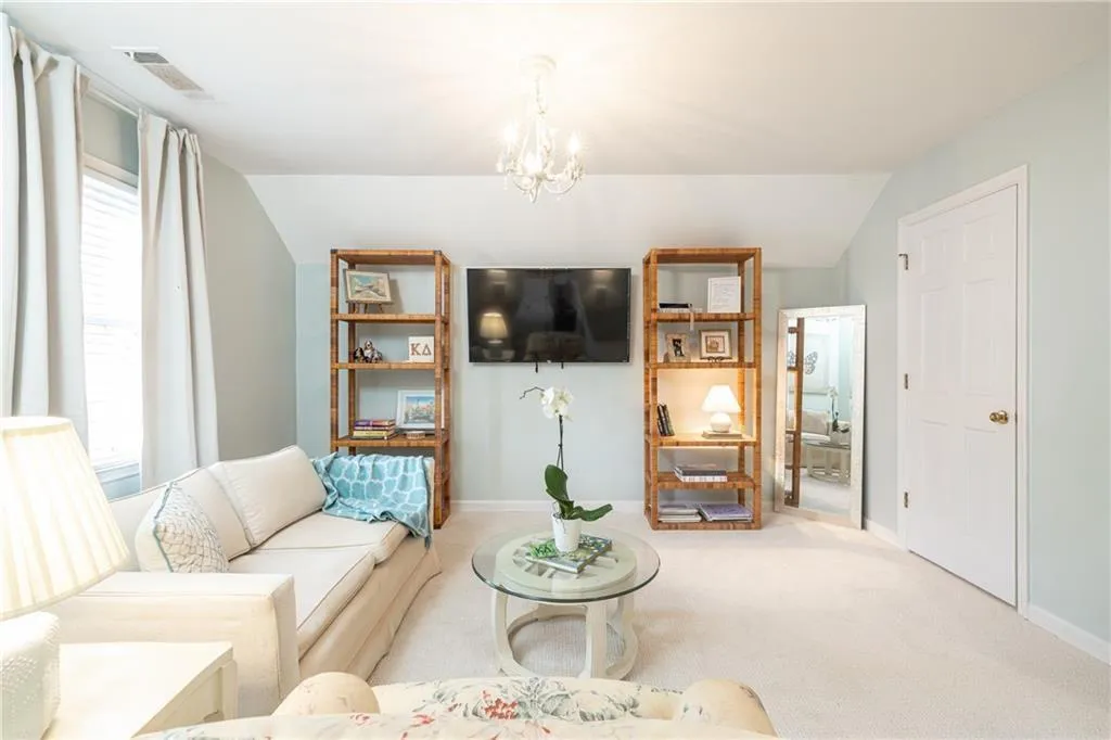 Carpeted living room featuring vaulted ceiling and a chandelier