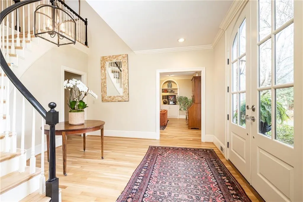 Foyer entrance with light wood-style flooring, crown molding, and suspended lighting