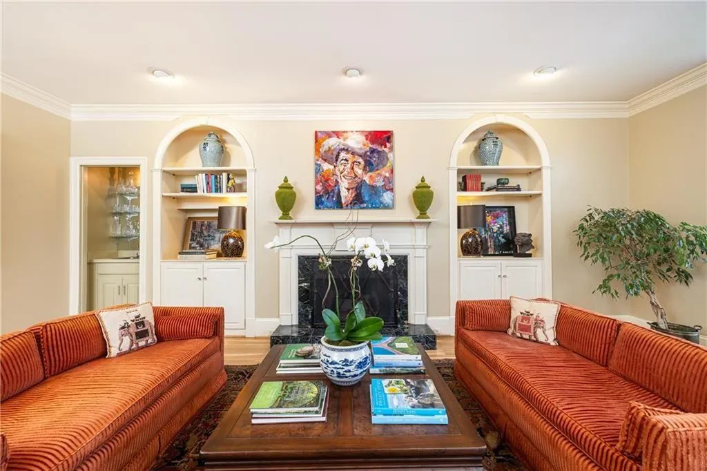 Living room featuring built in shelves, ornamental molding, wood finished floors, and a fireplace