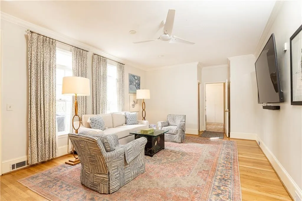 Living room featuring ornamental molding, light wood-type flooring, and ceiling fan