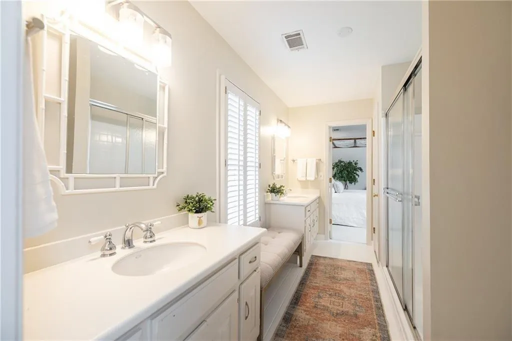Full bathroom featuring two vanities and a stall shower