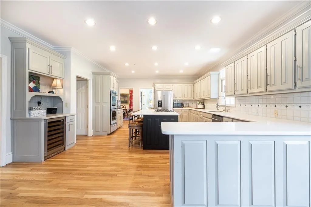 Kitchen with a breakfast bar, tasteful backsplash, wine cooler, a kitchen island, and ornamental molding