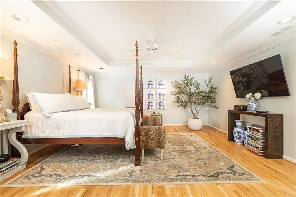 Bedroom with a raised ceiling, light wood-style floors, crown molding, a ceiling fan, and recessed lighting