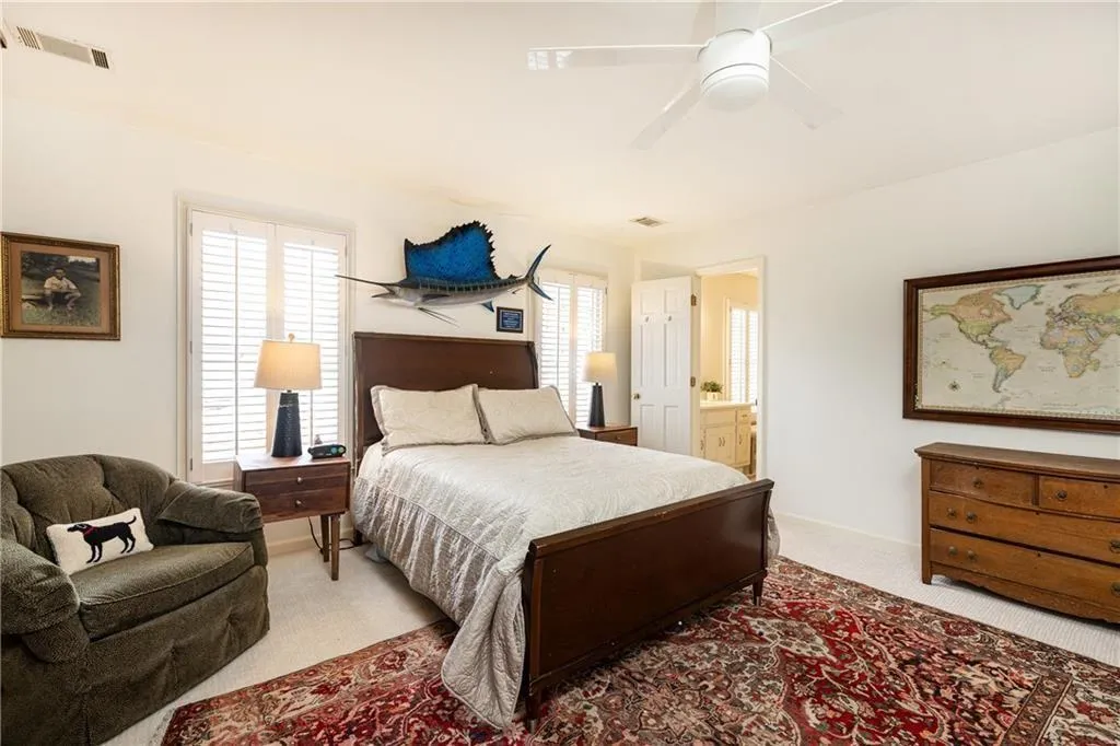 Bedroom with carpet floors, a ceiling fan, and connected bathroom