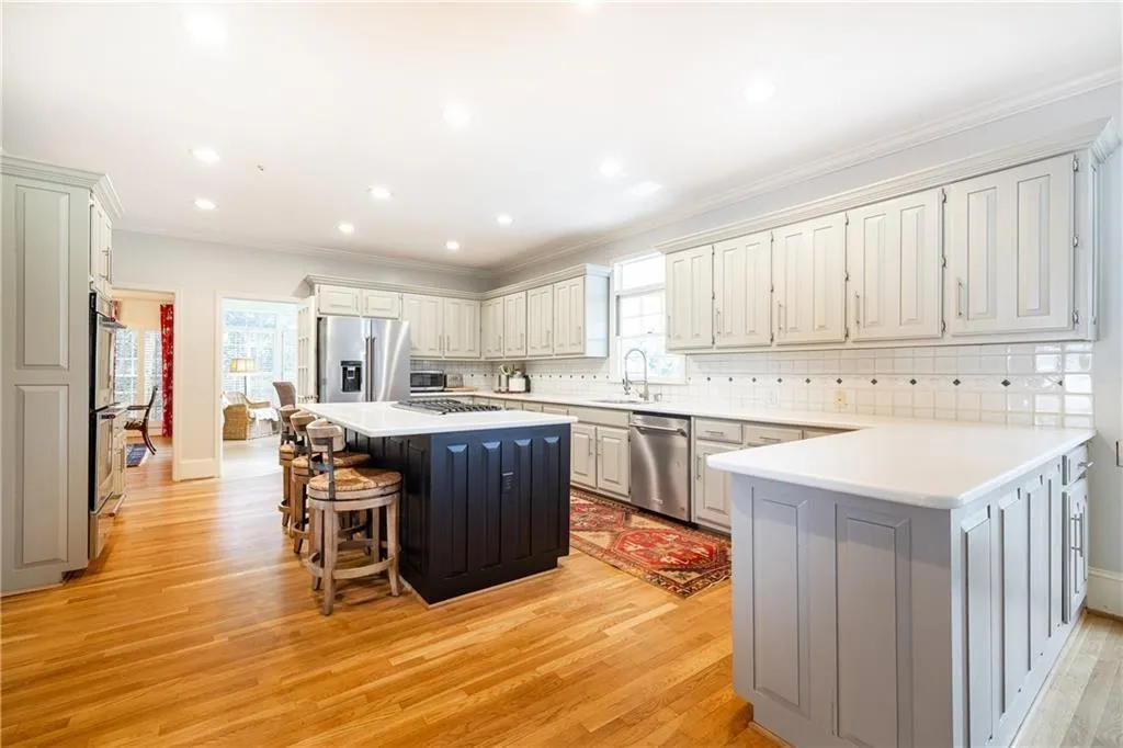 Dual tone kitchen with a breakfast bar, decorative backsplash, dual tone cabinetry, crown molding, and a peninsula