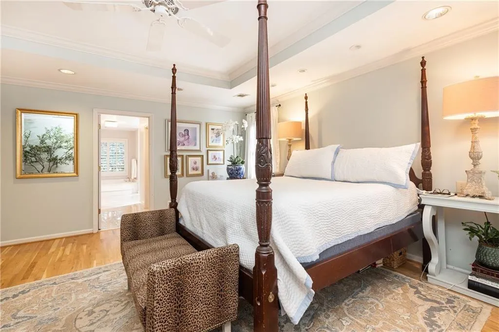 Bedroom with light wood-style flooring, crown molding, a ceiling fan, a tray ceiling, and recessed lighting