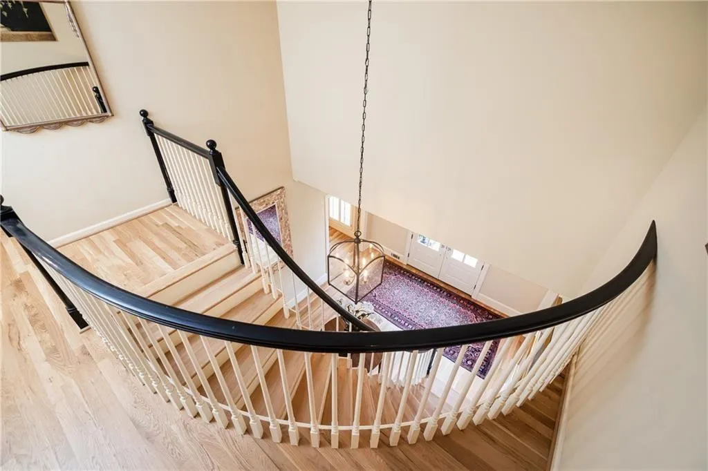 Stairs with a high ceiling, wood finished floors, and suspended lighting