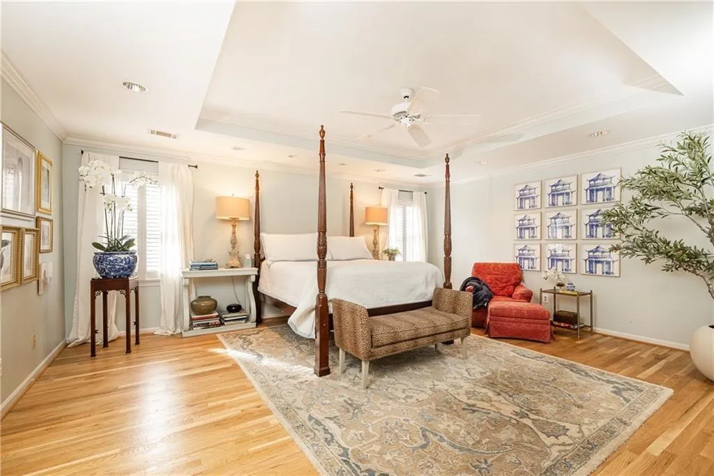 Bedroom with ornamental molding, light wood-style flooring, ceiling fan, and a raised ceiling