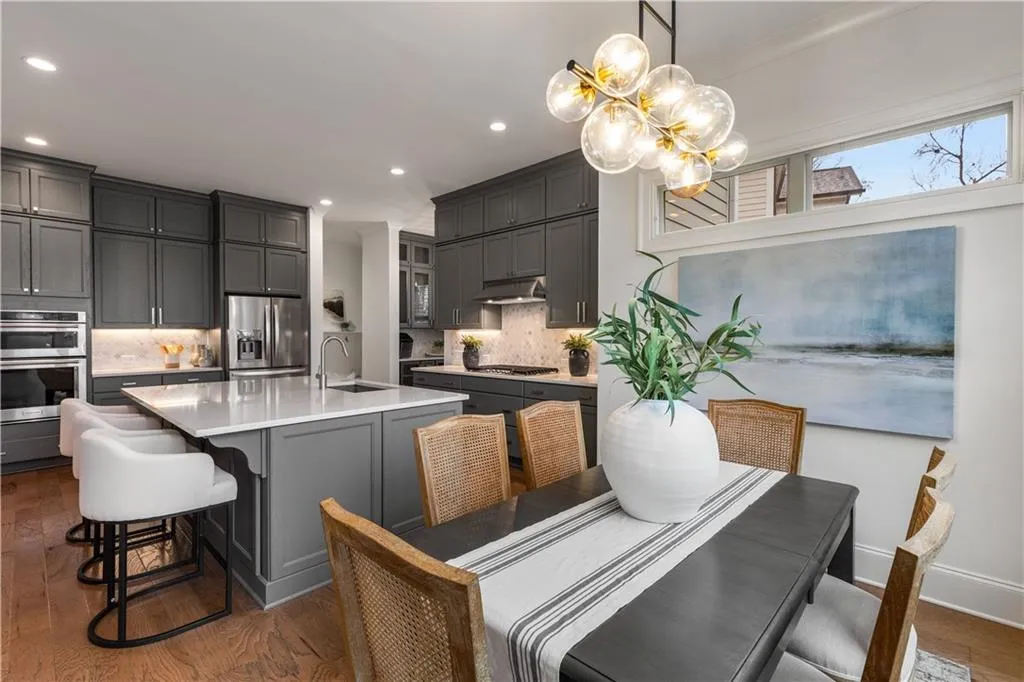 Kitchen with a breakfast bar, sink, hanging light fixtures, a center island with sink, and stainless steel appliances