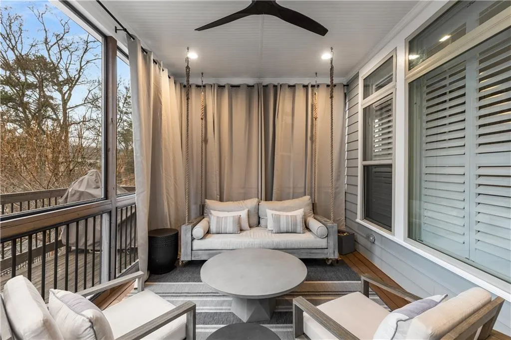 Screened in porch featuring ceiling fan and bed swing