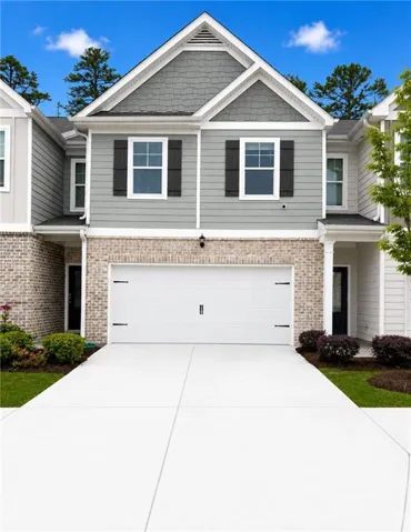 Contemporary townhome exterior featuring light gray siding with dark gray shake accents and a brick lower level