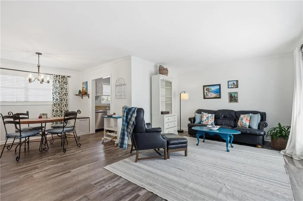 Living area featuring ornamental molding, light wood finished floors, and a chandelier