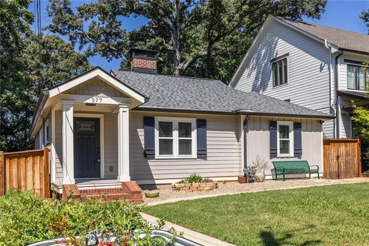 Cottage-style exterior featuring a covered entry, dark blue door, brick steps, and a shingle roof