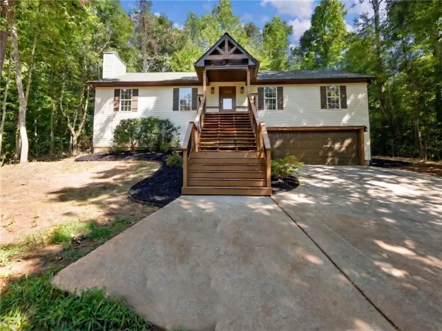 Elevated home featuring a prominent wood staircase leading to a covered entry with timber detailing