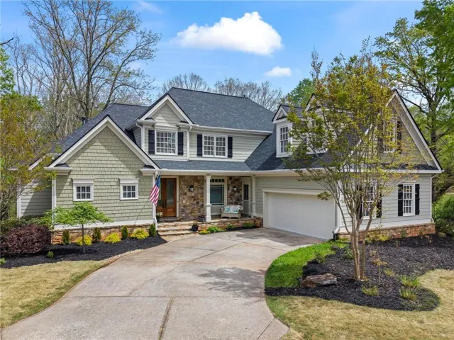 The property features a stone facade, dormer windows, and a two-car garage