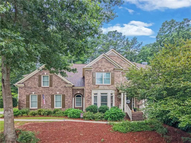 Brick facade residence featuring a prominent bay window, gabled rooflines, and decorative window shutters