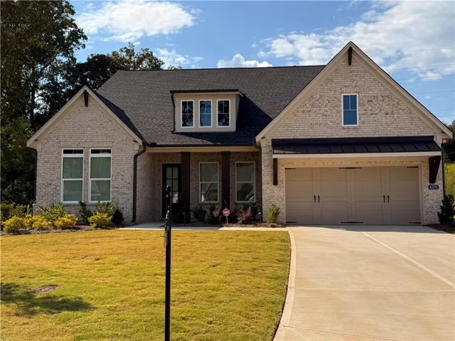 Craftsman-style home featuring driveway, a front yard, a porch, brick siding, and a shingled roof