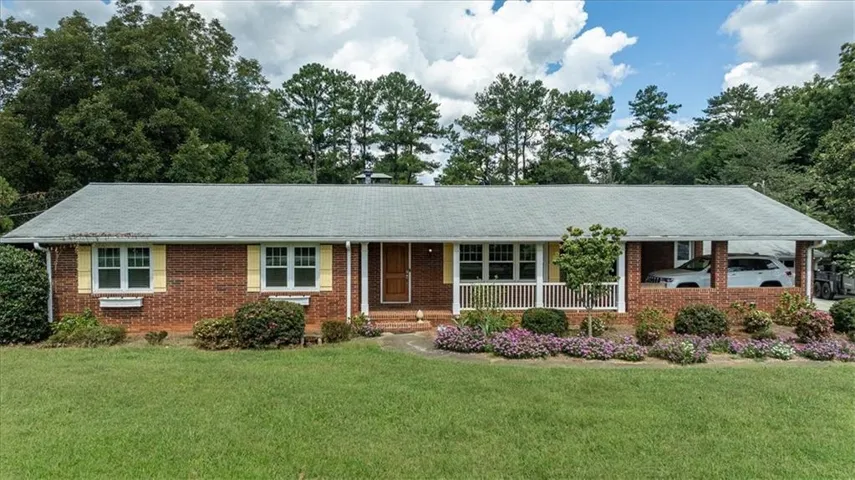 Brick exterior with a covered front porch, white railing, and an attached carport