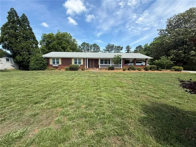 Traditional brick ranch home with a covered front porch and a two-car carport