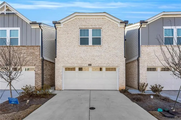 Contemporary townhome featuring a light brick facade and an integrated single-car garage with transom windows