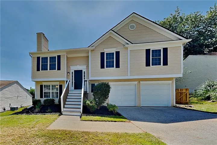 Exterior featuring light-colored siding, dark shutters, an attached two-car garage, and a prominent front entry staircase