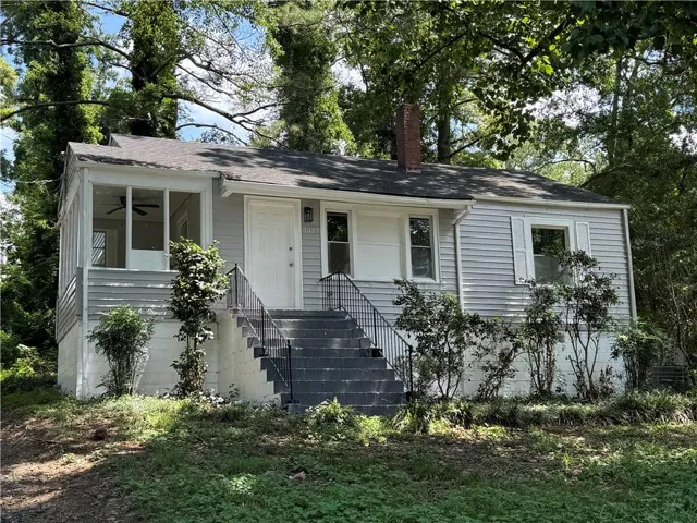 View of front of house with ceiling fan, stairway, a chimney, and a shingled roof
