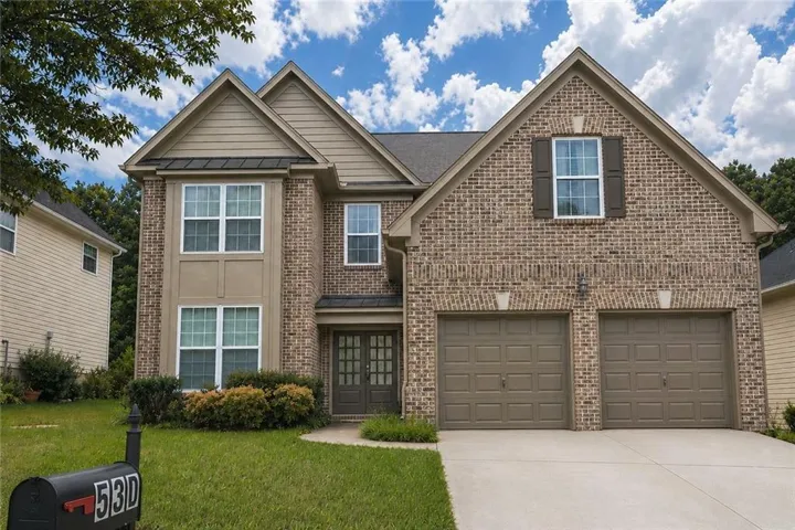 Brick and siding exterior featuring a two-car garage with panel doors, a double front entry door, and a concrete driveway