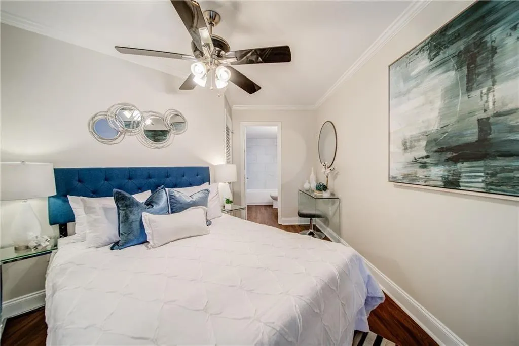 Bedroom featuring crown molding, dark wood-type flooring, ensuite bath, and ceiling fan