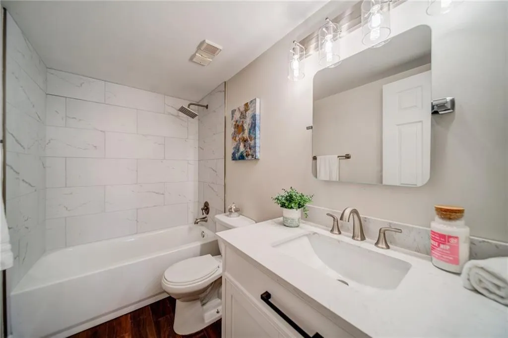 Bathroom featuring vanity,  shower combination, and dark wood-style floors