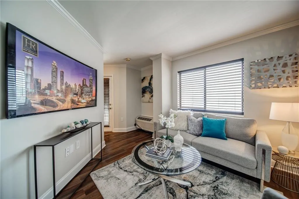 Living area featuring dark wood-style floors, crown molding, and an AC wall unit