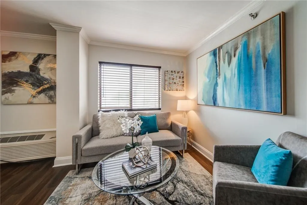 Living room with crown molding, wood finished floors, and an AC wall unit
