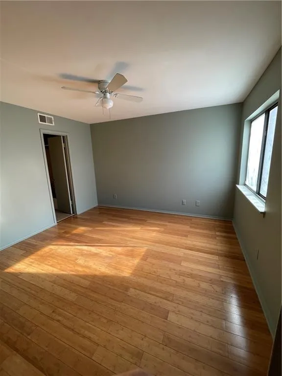 Empty room with light wood-style flooring and a ceiling fan