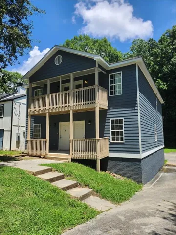 Two-story building featuring dark blue siding and a painted brick foundation