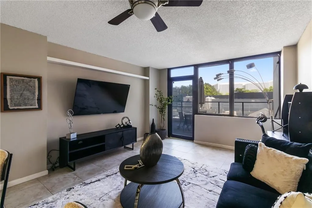 Living room with a ceiling fan, tile patterned floors, baseboards, and a textured ceiling